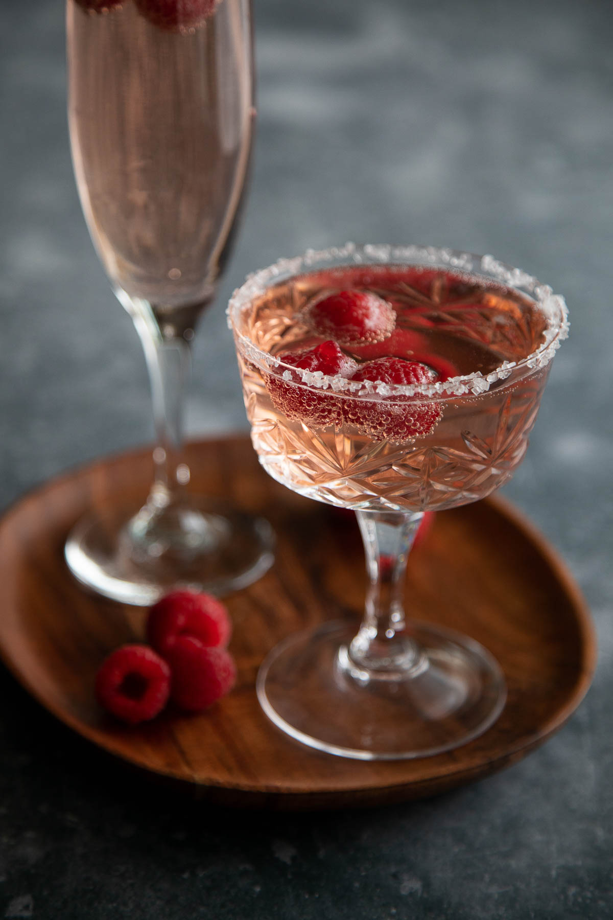 raspberry rosé sprite cocktail in champagne coupe on brown plate