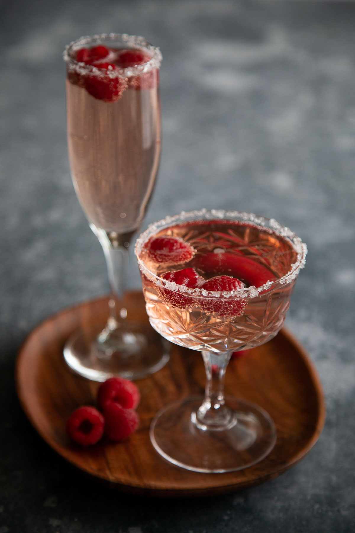 raspberry rosé cocktail in champagne coupe on brown plate