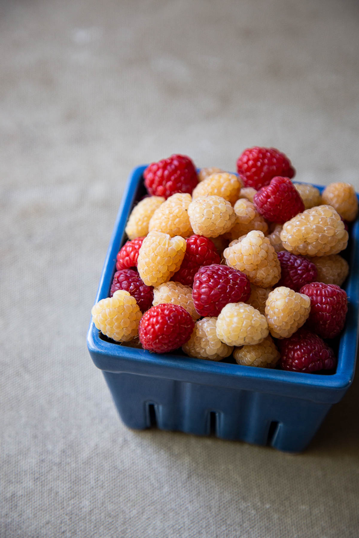 White & Red Raspberries in Blue Basket