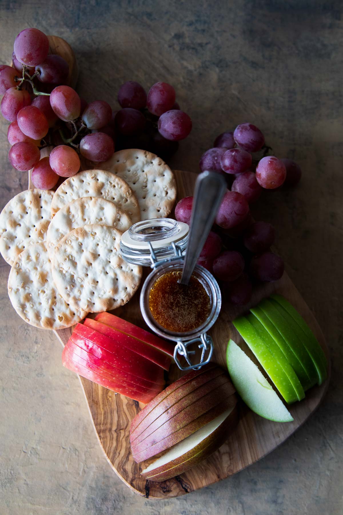 Fruit Appetizer Board with sliced pears, apples, persimmons, crackers and honey