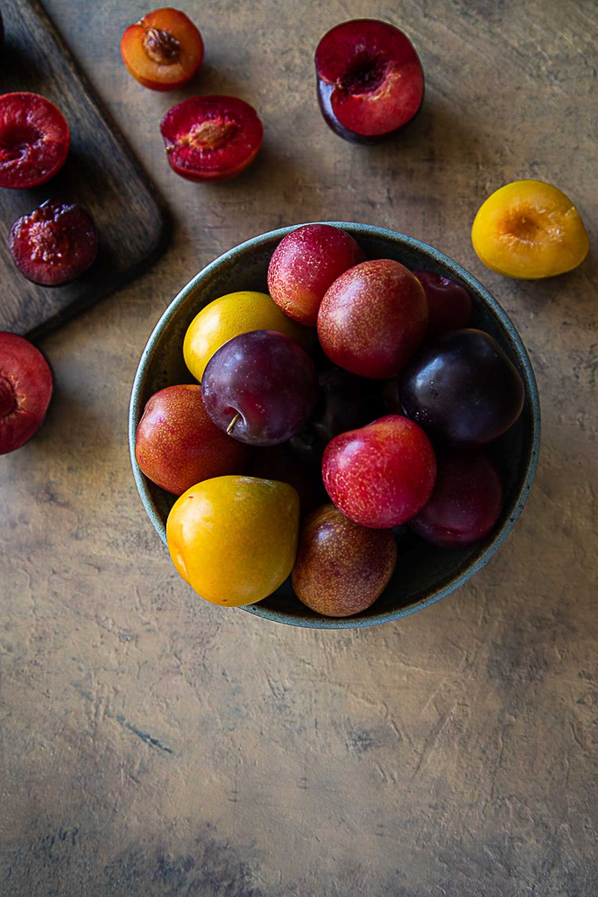 fresh plums in bowl and cut open on table