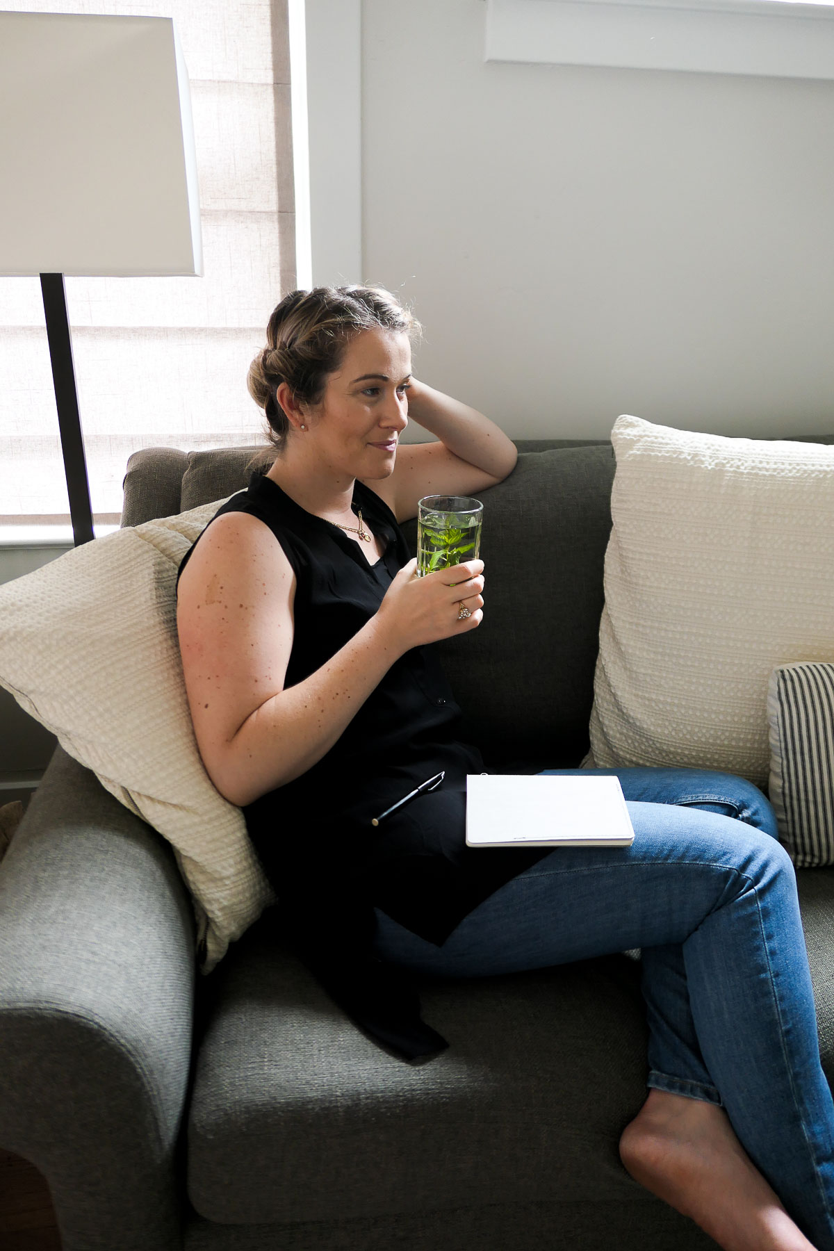 Woman drinking fresh peppermint tea in Eileen Fisher Black Tank and Everlane Jeans.