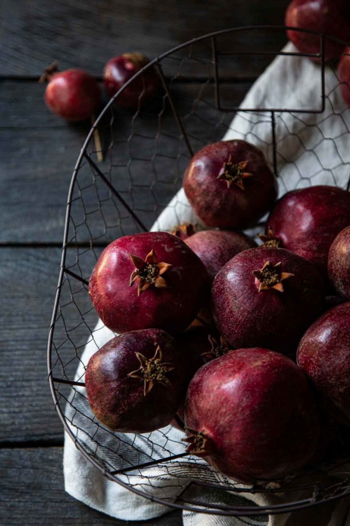 pomegranates on dark table in basket - fall and winter appetizers