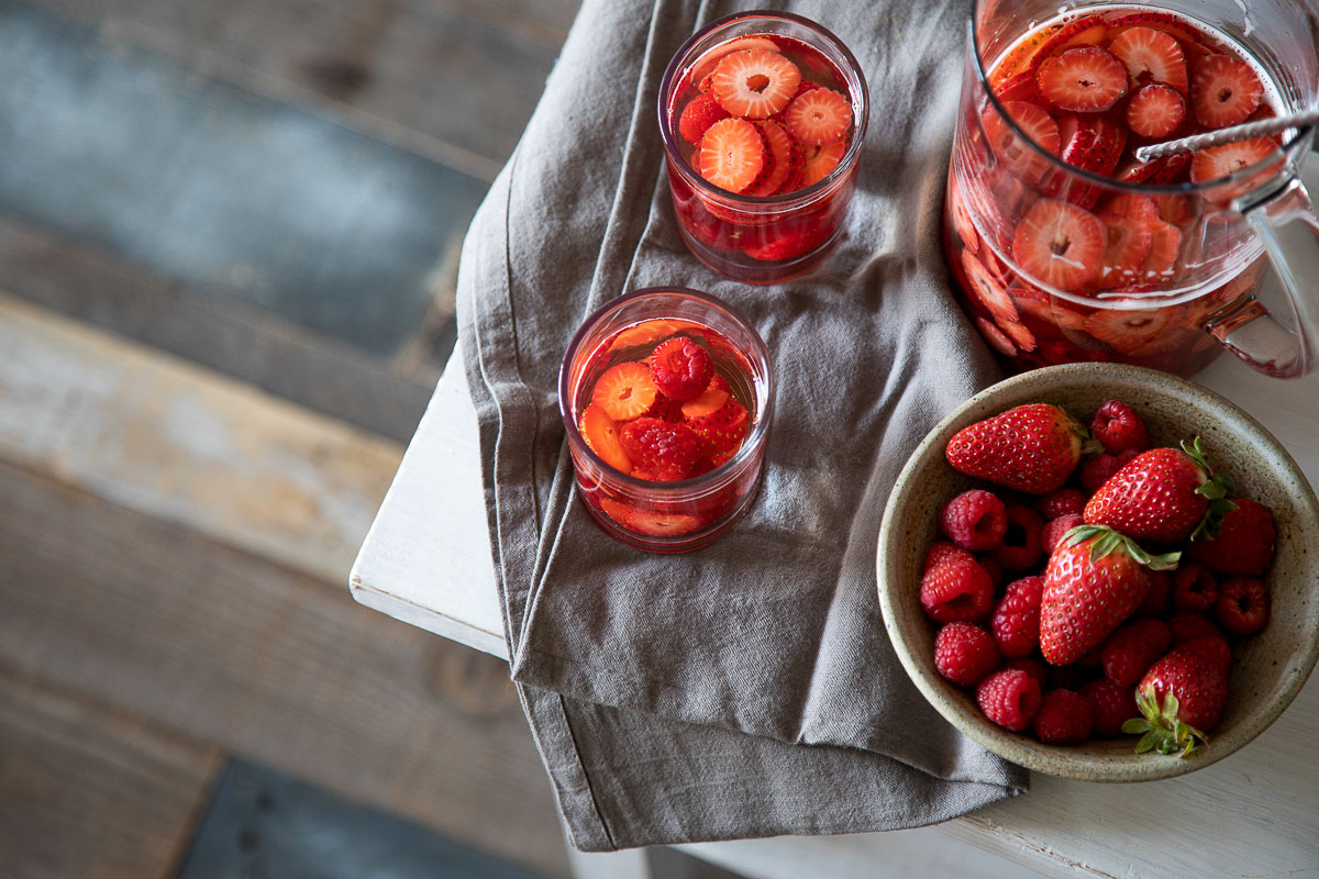 Spring sangria in pitcher and glasses on table with gray napkin.