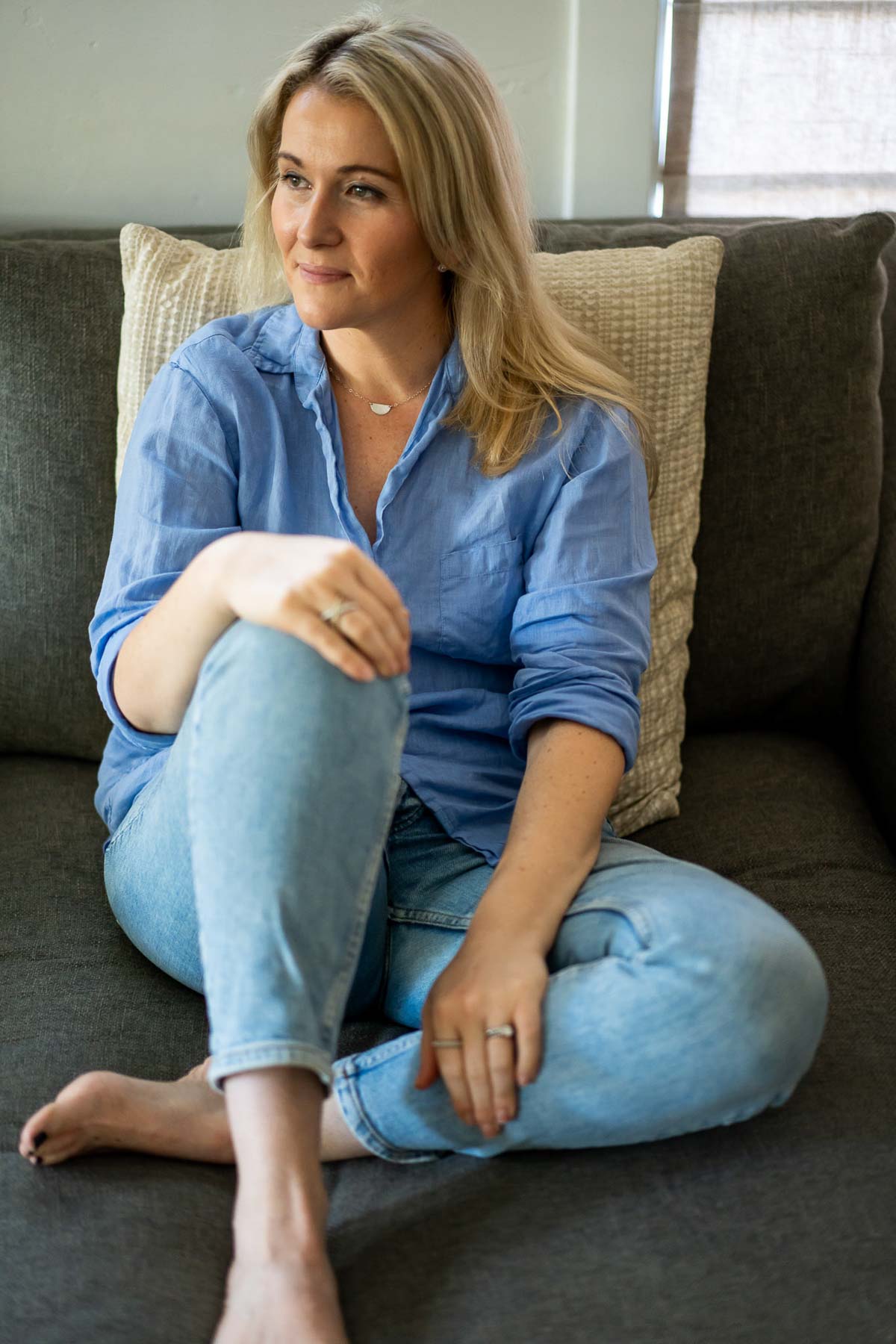 Luci Wearing Blue Linen Shirt and Jeans on Couch