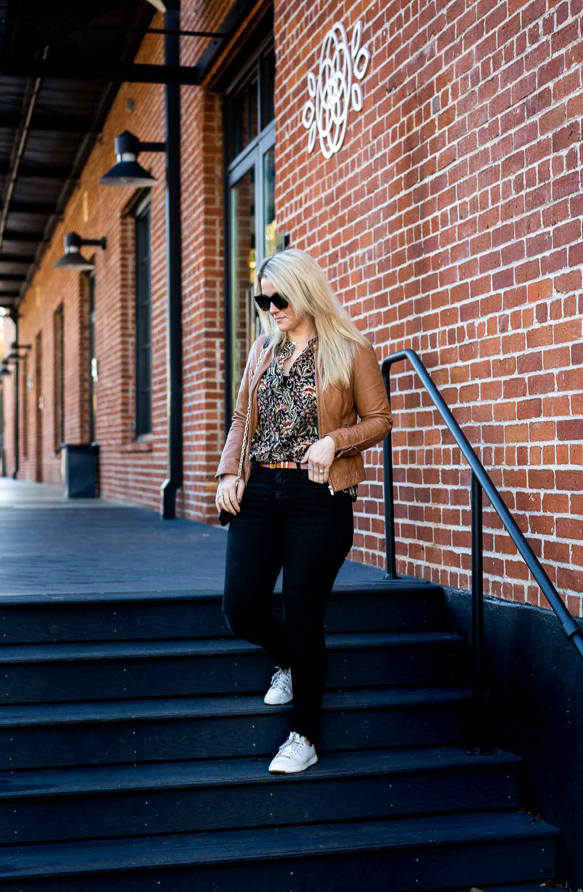 Black Wash Jeans Outfit with floral print blouse and tan leather jacket