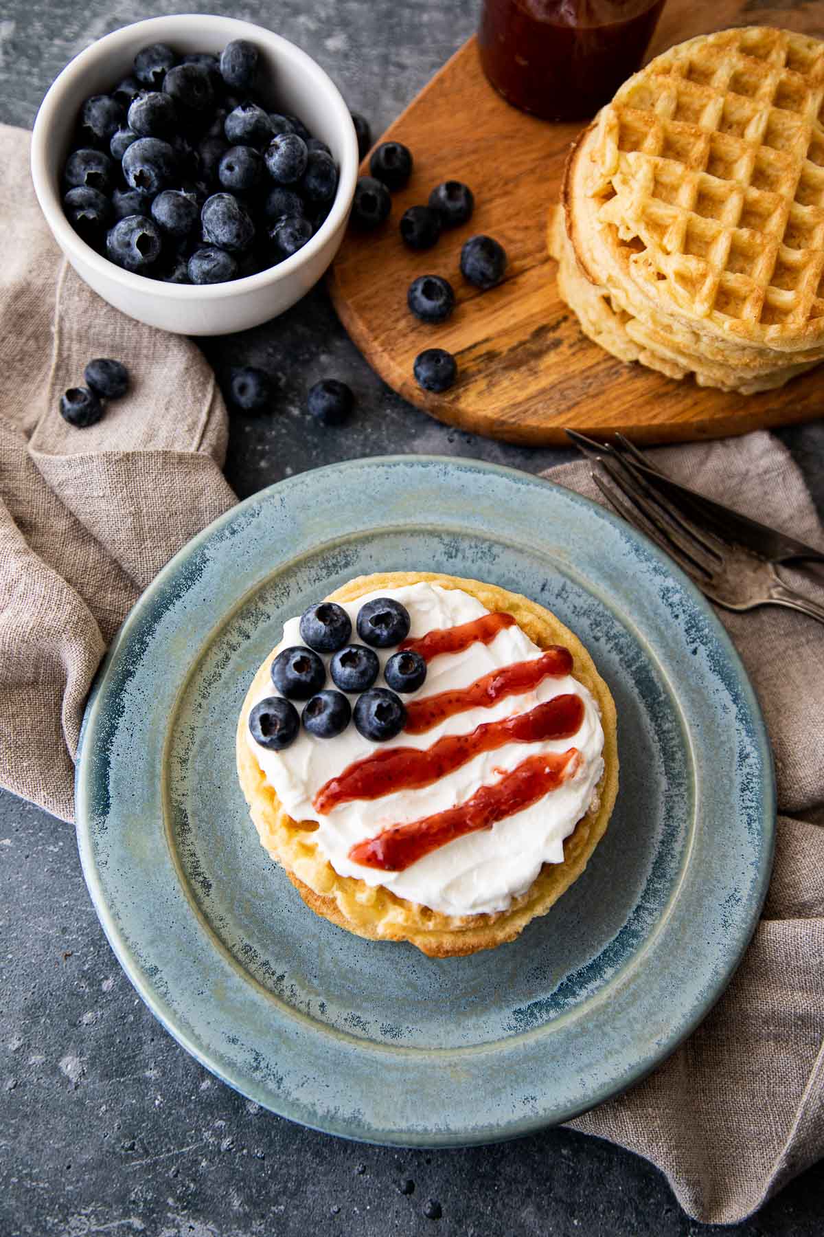 Waffles topped with yogurt, strawberry jam, and blueberries to make flag waffles