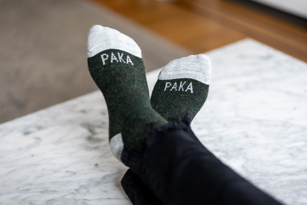 Sustainable Socks - Paka socks - feet cross on table wearing green PAKA socks