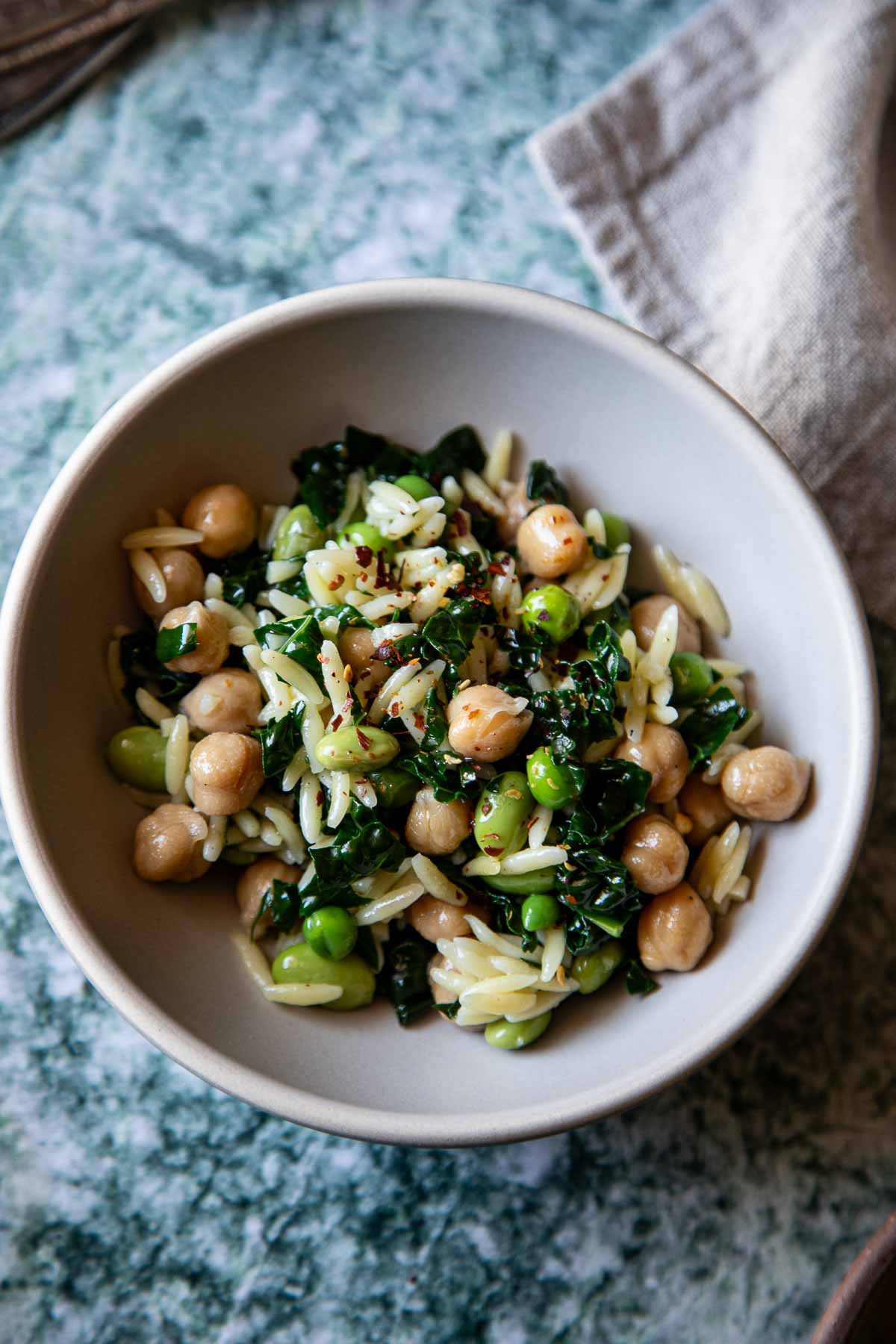Orzo, pasta, spinach, and garbanzo beans on light pink plate