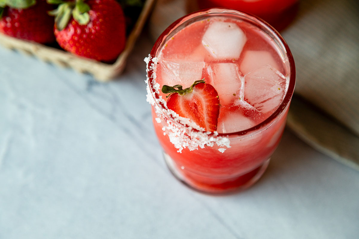 strawberry margarita on the rocks in 1 glass with salt rim