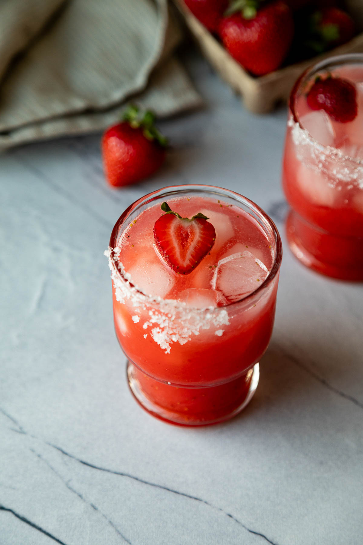 homemade strawberry margarita on the rocks with half strawberry laying on top