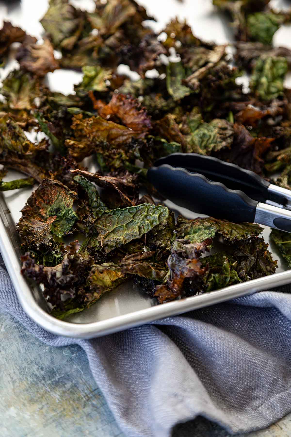 Easy Baked Kale Chips on sheet pan with tongs