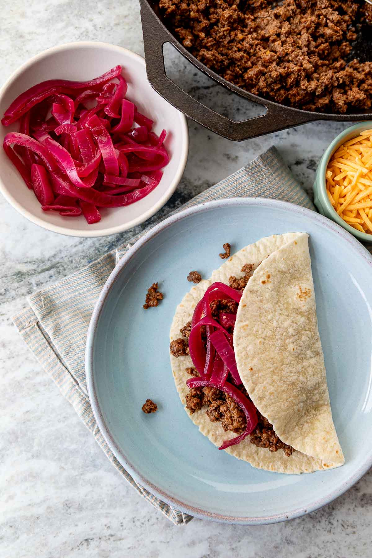 Homemade taco meat served in a corn tortilla with quick pickled onions
