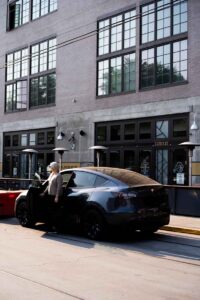 What to Keep In Your Car - luci standing by Tesla Model Y in Sacramento