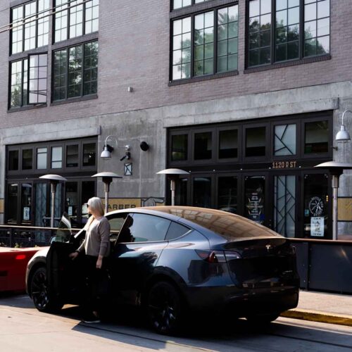 What to Keep In Your Car - luci standing by Tesla Model Y in Sacramento