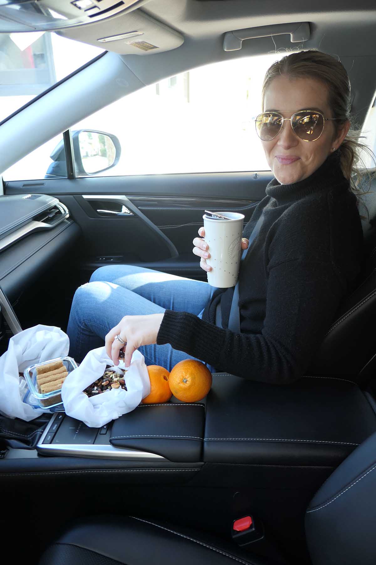 What to Keep In Your Car - Luci holding reusable coffee cup with sustainable snacks in the center console