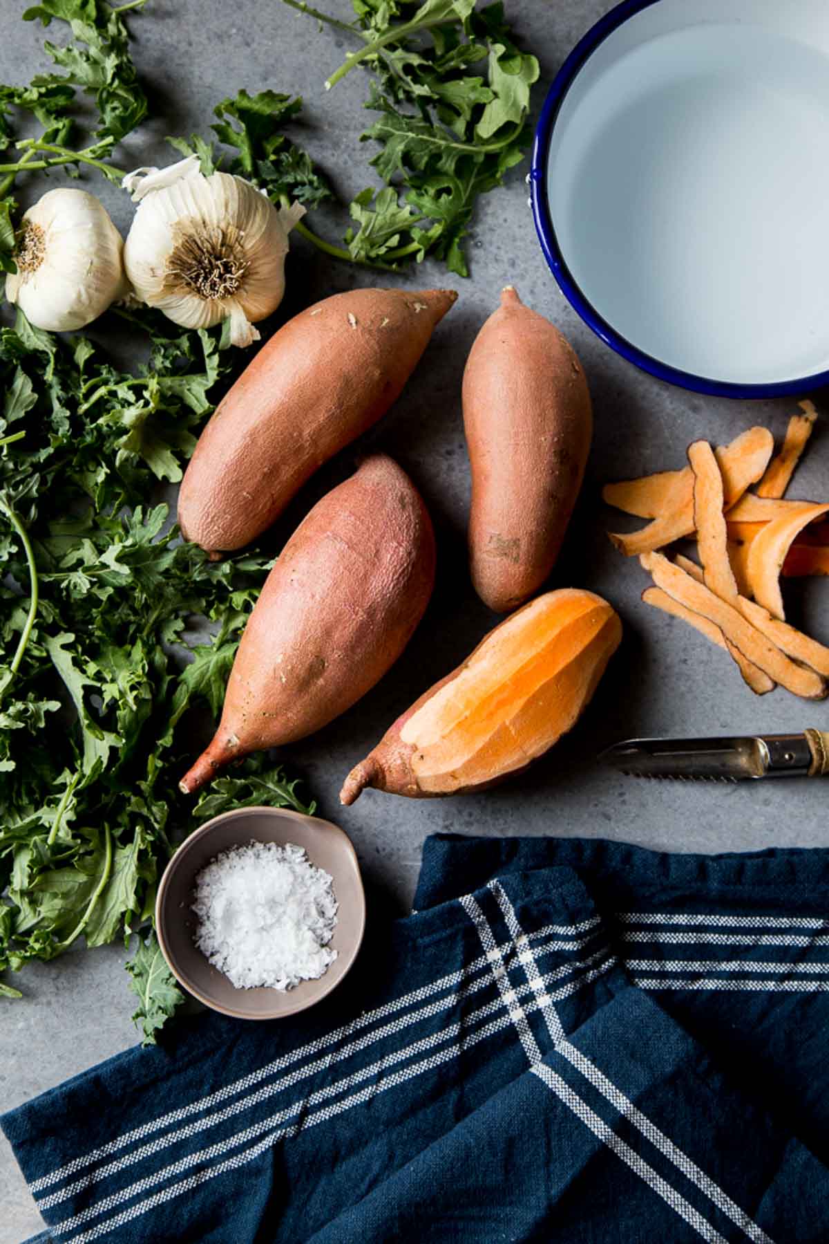 Peeled and raw sweet potatoes on tablecloth with garlic and salt peeling sweet potato - how to store sweet potatoes