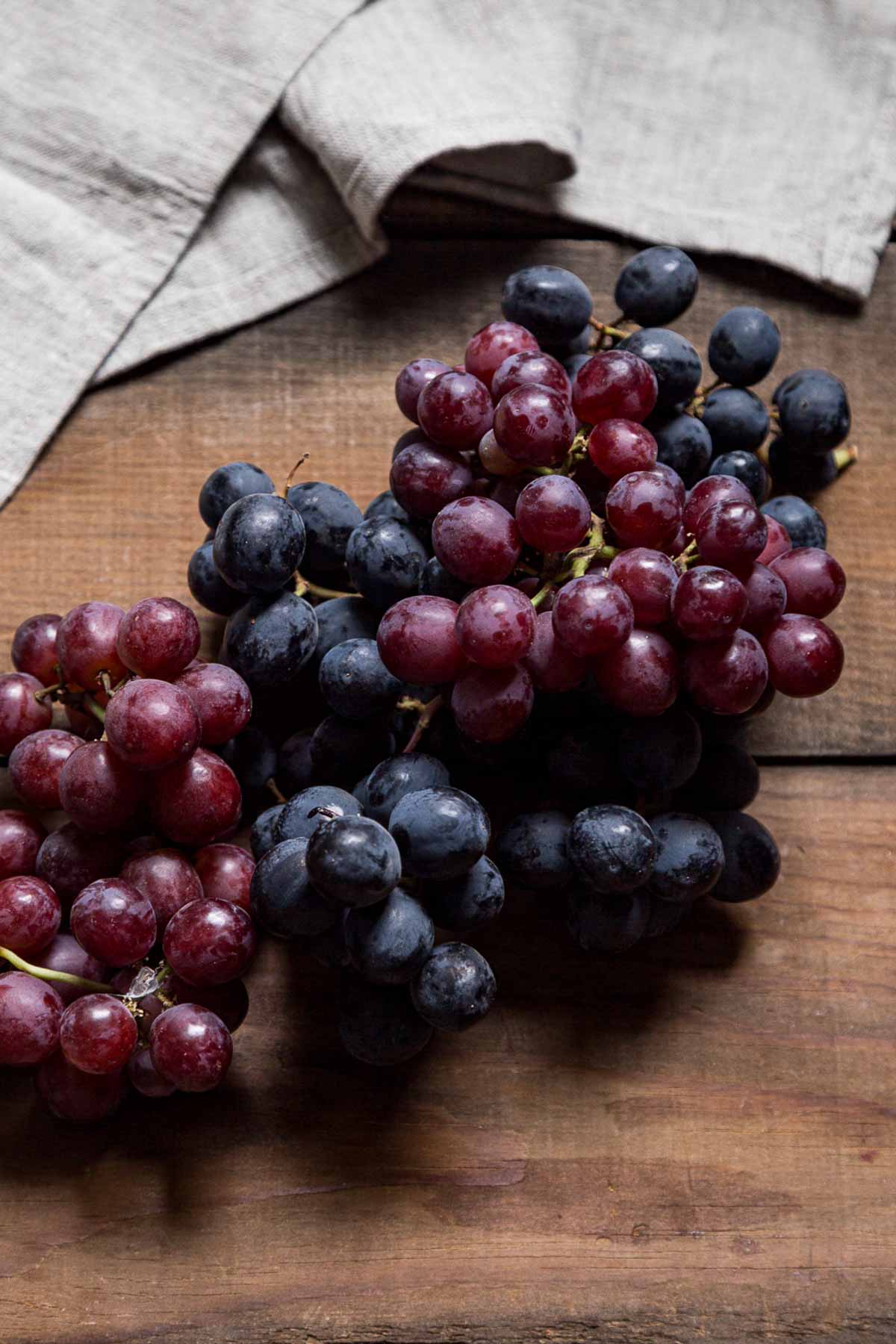 when are grapes in season - red and concord grapes on a wood slab