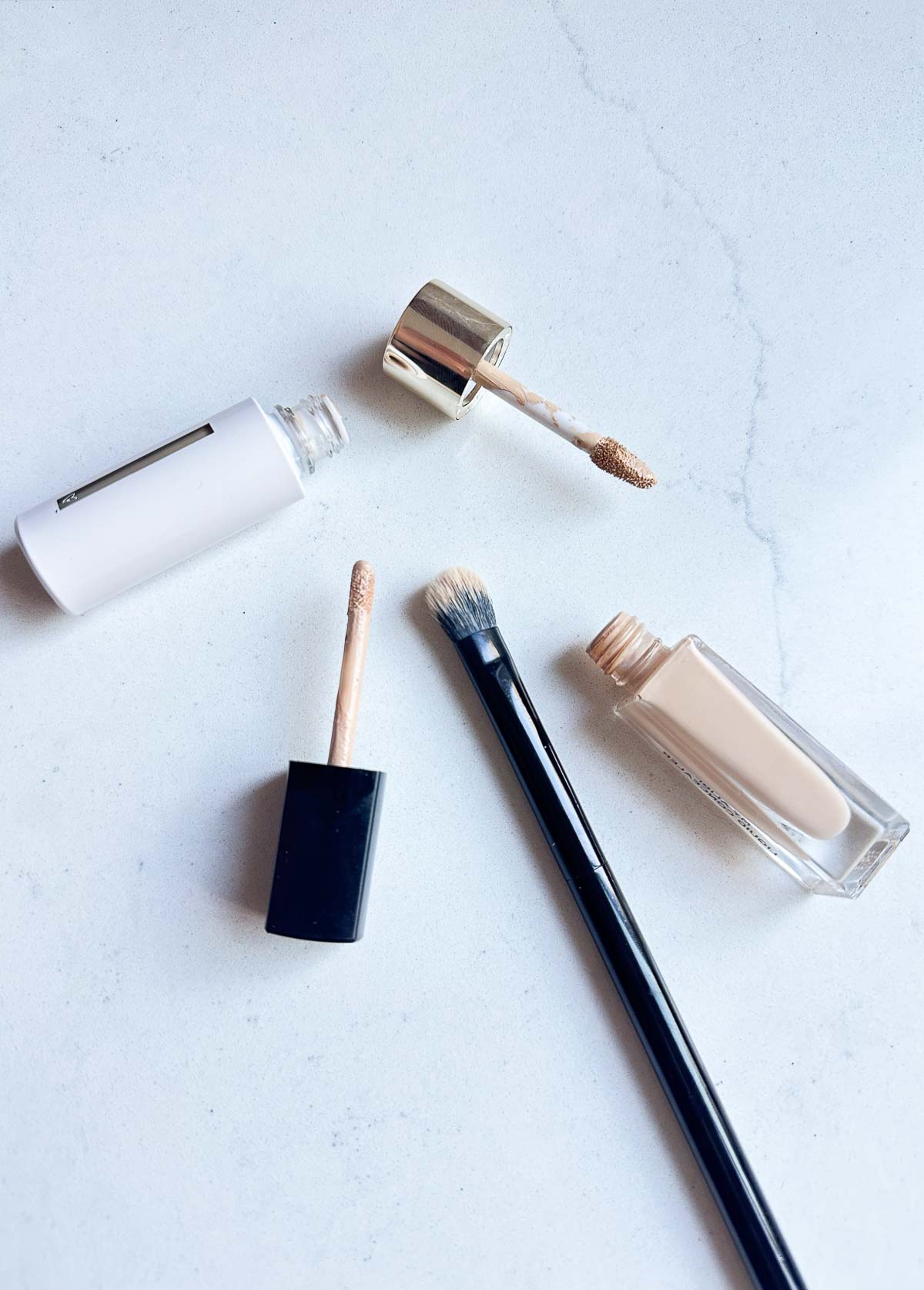 two concealers opened with doe foot applicators and brush nearby Best under eye concealer for mature skin 12